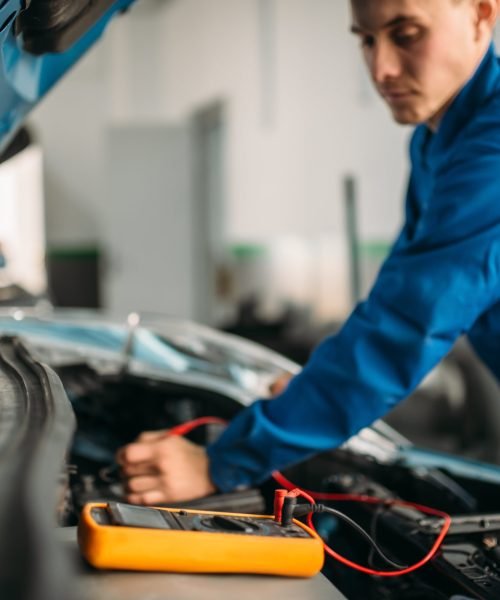 car-repairman-with-multimeter-battery-inspection-min-scaled.jpg